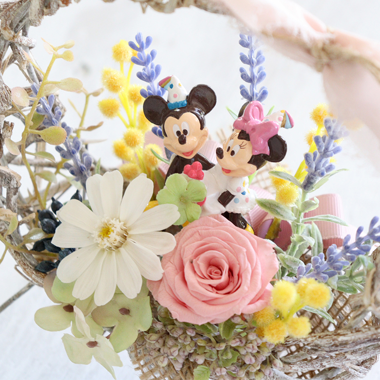 春らしいホワイトのジニアとピンクのバラにミモザやラベンダーお花いっぱいのバスケット
